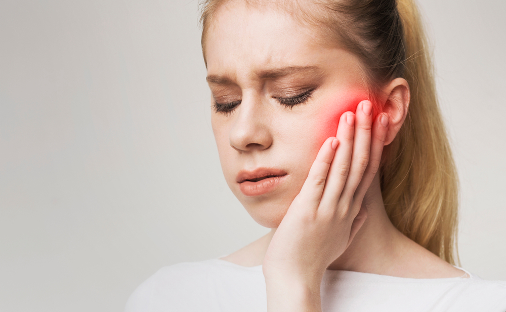 fille ayant une douleur dû à une douleur à la mâchoire